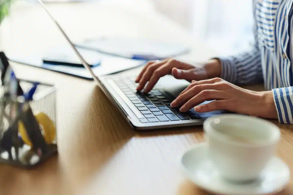 A web developer works with a cup of coffee at her side.