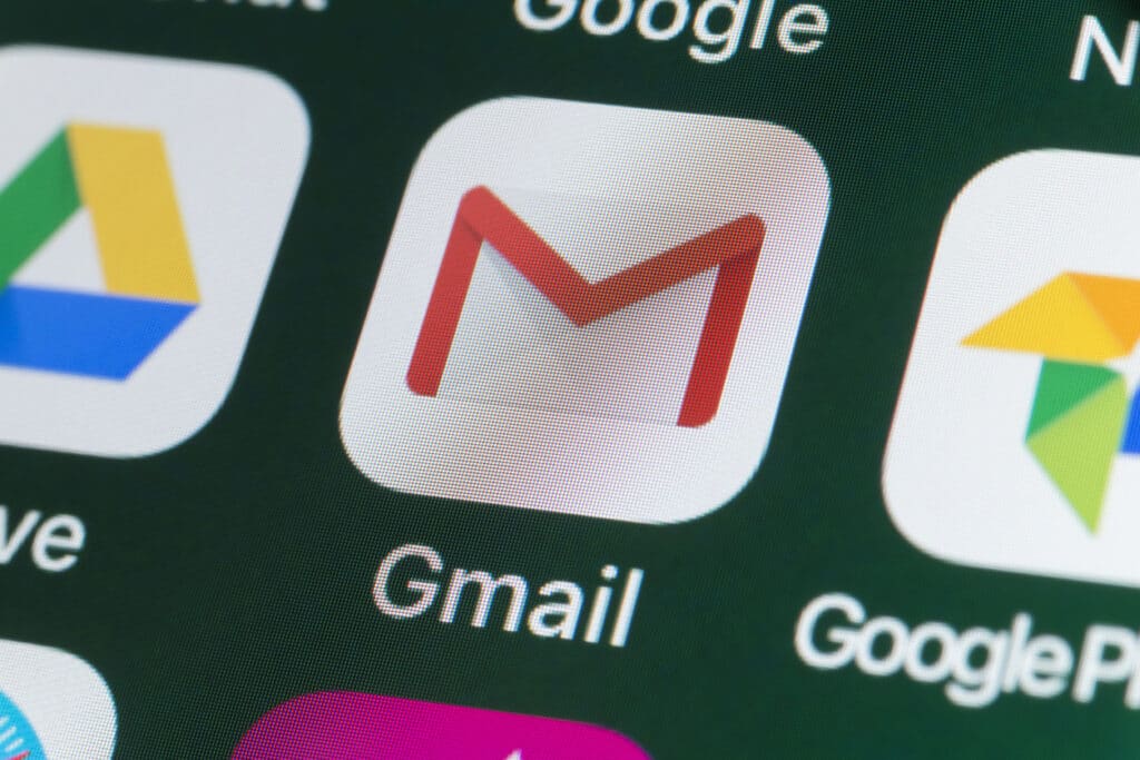 Close-up icon of Gmail on a phone screen with a dark green background
