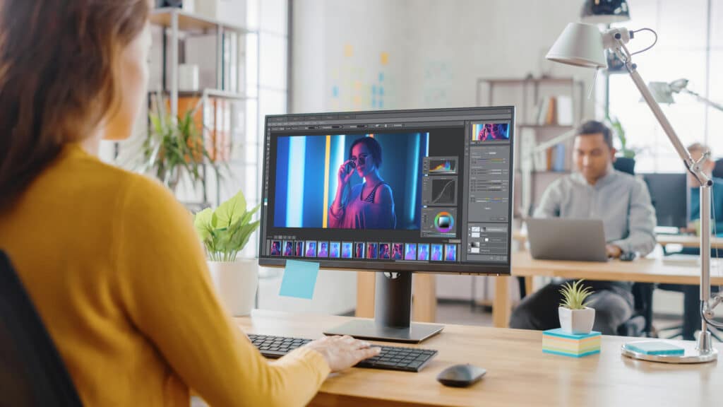 A woman resizes images in Photoshop while working in a shared office