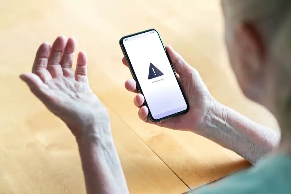 An elderly man holds his hand up in frustration as a page fails to load on his mobile device.