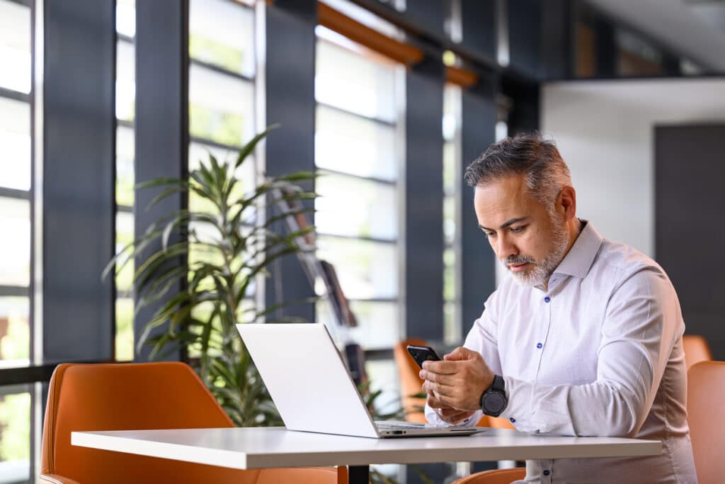 Portrait of a mature businessman with focused expression sitting at a table with his laptop