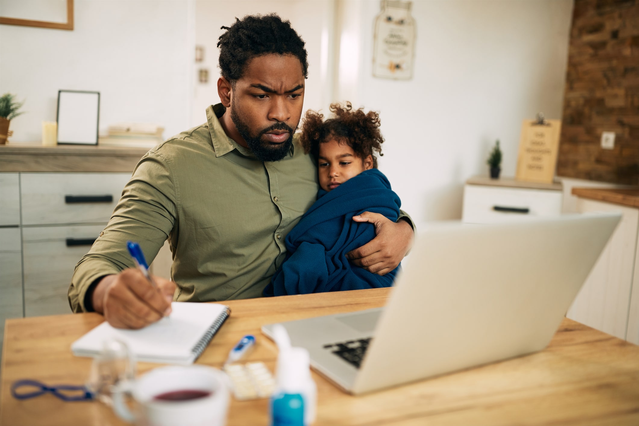 Single father taking care of his daughter while writing cold emails on laptop at home.