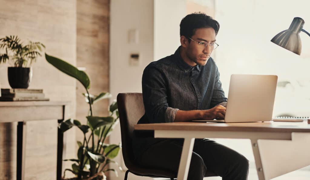 a man studies his laptop intently reviewing results from his email warmer