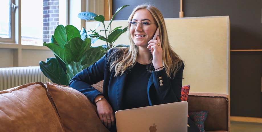 A businesswoman sitting and wearing a white suit checks digital marketing results on a laptop